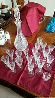 Overview of entire lot on table showing one large decanter with stopper, multiple glasses arranged in front including two types, and a toothpick holder.