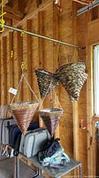 Photo showing five hanging woven baskets in garage on wooden beam, different sizes and hanging mechanisms visible