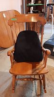 Front view of wooden rocking chair with black lumbar cushion on seat