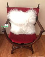 Front view of the wood frame chair with red velveteen upholstery and white faux fur throw pillow.