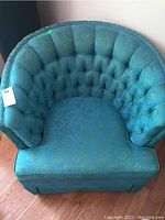 Full front view of the teal vintage armchair showing tufted detail and fabric pattern