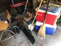 Overview photo showing the shovel, boots, boots, coolers and stool arranged in a garage space.