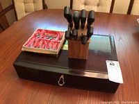 Overall view of lot including fork box, wooden knife block, and knives arranged on table.