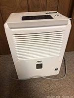 Front view of white Cool Works dehumidifier with air outlet grille and top control panel.