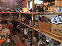 Wide view of wooden shelving fully loaded with assorted hardware, tools, boxes, and containers including a yellow hard hat and various cans.