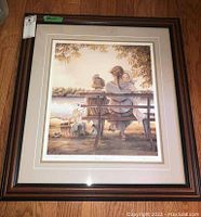 Full view of framed print showing mother and children on bench by water with warm tones.