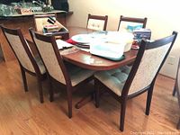 Full view of teak table with leaf installed and six chairs around it