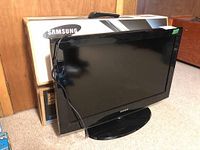 Samsung 32 inch TV displayed with remote on top and box behind, placed indoors.