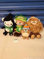 Four stuffed mascots from the 2010 Winter Olympics characters Miga, Sumi, Mukmuk and Quatchi gathered together showing full front views.