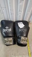 Pair of black Spartan adult boxing gloves, showing wear and usage marks