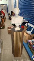 Photo of white classical female bust on hexagonal stand in storage hallway