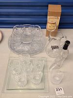 Overall view of the glassware lot, including the sectional tray, glasses, jug, and shoe-shaped bottle arranged on a table surface.