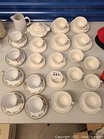 Photo of multiple La Cartuja de Sevilla teacup and saucer sets including sunflower pattern, and a white dish with lid.