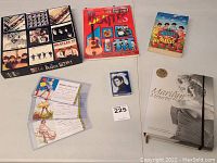 Overview of Beatles puzzle box, Beatles book with guitar, small Beatles item, playing cards, and Marley Monroe set on table