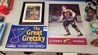 Photo showing the signed Wayne Gretzky poster, framed Sports Illustrated magazine cover, and St. Louis Post-Dispatch Gretzky sign together on a table.