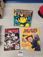 Photo showing all three items: X-Men pop-up book, MAD magazine, and Wolverine comic book together on a table.