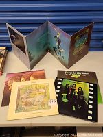 Photo showing multiple vinyl records, including a gatefold album opened with fantasy artwork visible, and other records spread on a table.