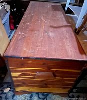 Side view of the oversized cedar chest showing solid wood construction and surface wear; dusty finish with some scratches visible