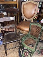 Photo of all four assorted chairs together showing large leather chair, vintage wood chair, Victorian parlor chair, and green painted child rocker with broken cane seat.