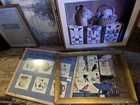 Photo showing assorted framed art, including a print with birds, tea-themed art with teapots, and a large wood frame on floor