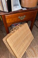 Photo showing wood side table with drawer and picnic basket placed in front
