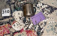 Overview of jewelry and antique child's silver cup on patterned carpet, assorted earrings and charms visible