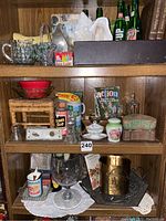 Full frontal image of shelves showing assorted vintage glassware, planters, advertising boxes, and bottles on wooden display.