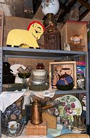 Full view of three shelves filled with various vintage collectibles including glassware, ceramics, and decorative items.