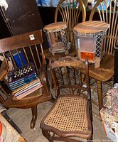 Two wooden chairs with swivel bases, two wooden chairs behind, stack of books on a carved vintage chair, handmade lucite display cabinets on wood chairs, showing details of wood and condition.