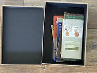 Open shoebox with approx 50 assorted Canada Post First Day Cover pamphlets from the 1970s and 1980s