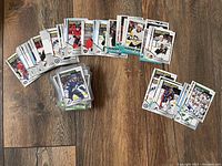 Spread of various 2021 O-Pee-Chee hockey cards including rookies, award winners, inserts, displayed on wooden floor.