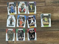 Multiple NBA Hoops basketball cards laid out on a wooden floor showing different players in various team jerseys including Philadelphia 76ers, Los Angeles Lakers, Brooklyn Nets, and others.