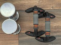 Top view of two chrome 15 lb YORK dumbbells and two Nike pushup bars with padded handles and black base supports on a wooden floor.