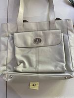 Front view of cream Danier leather tote with flap pocket and twist-lock closure.