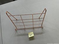 Rose gold colored kitchen book holder stand on flat surface showing side angle and construction details