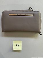 Closed front view of taupe Steve Madden wallet showing metallic logo plaque