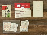 Various Canadian stamp booklets and souvenir cards alongside sheets of postage stamps.