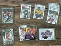 Photo of various hockey cards laid out on wooden surface, showing several different players and card designs.
