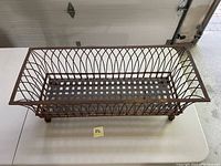 Top view of one metal outdoor planter basket showing rectangular lattice bottom and curved wire sides with patina and rust