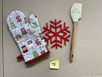 Photo showing all three items: oven mitt, snowflake trivet, and spatula with text 'OH FOR THE HOLIDAYS'