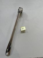 Full view of the metal shoehorn showing entire length and skull top handle.