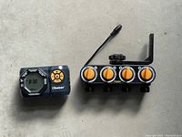 Digital control unit and 4-valve hose splitter laid side by side on a concrete surface