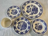 Various pieces of Royal China Underglaze dinnerware including plates, bowls, teacups, and saucers all featuring blue Asian-style patterns.