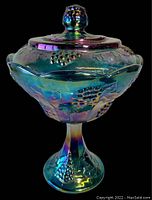 Full front view of the carnival glass candy bowl with lid, showing the iridescent finish and grape leaf pattern.