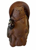 Front view of the Japanese bear figurine showing the facial details, large hat, and items held in paws.
