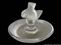 Clear glass ring dish with frosted bird figure in the center shown angled from the side.