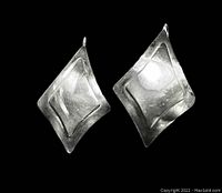 Front view of the pair of diamond-shaped sterling silver earrings on a black background showing the raised diamond design.