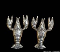 Front view of pair of sterling silver lobster shaped earrings on black background showing detailed features.