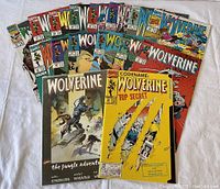 Collection of 16 Wolverine comic books laid out showing various covers including The Jungle Adventure and a bright yellow Codename: Wolverine Top Secret comic.