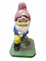 Front view of the vintage 19 inch concrete garden gnome showing paint wear on red hat, blue shirt, yellow pants, and green base with black shoes.